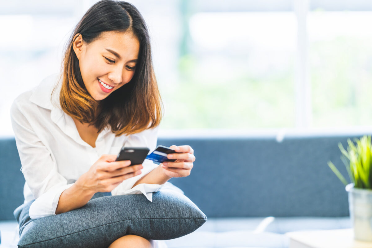 Young woman using smartphone and credit card for online shopping
