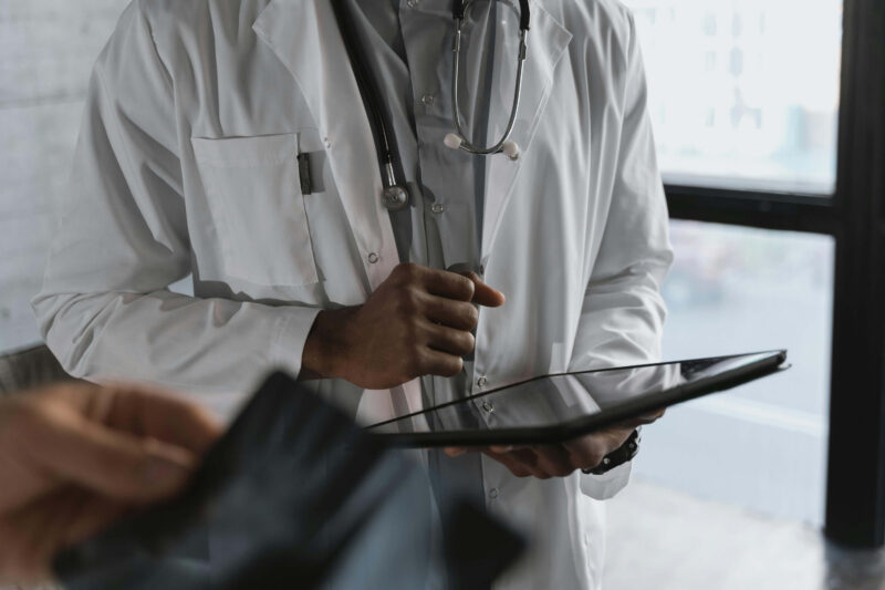 Doctor using iPad with patient nearby