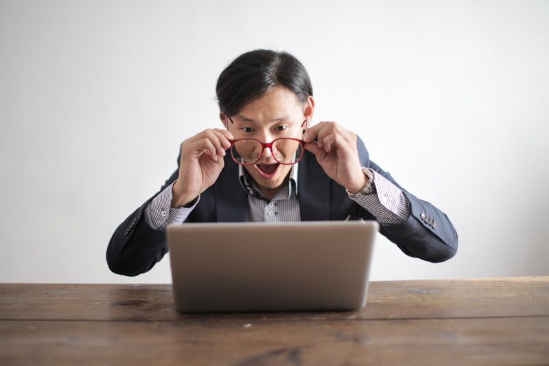 Person with glasses surprised at computer